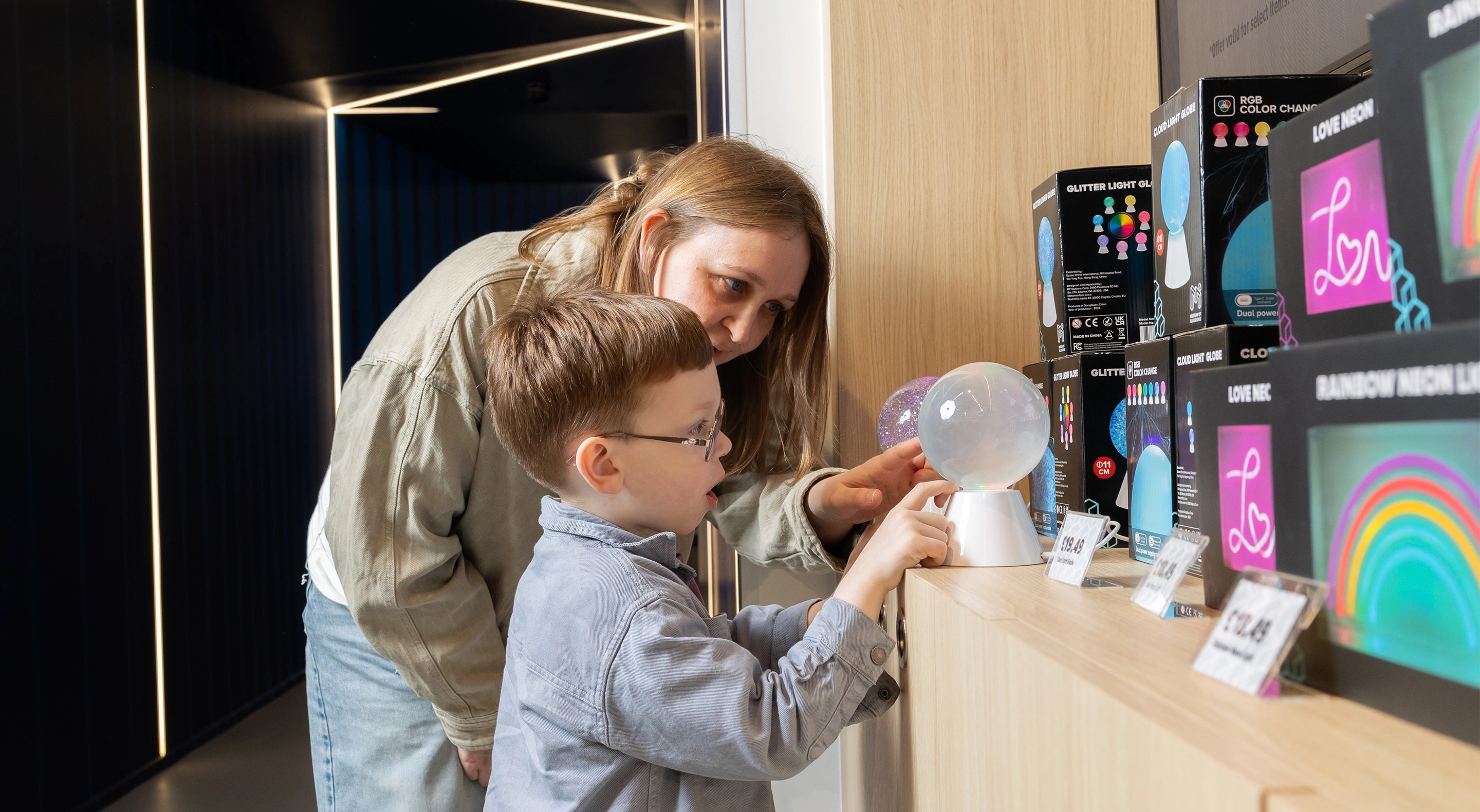 A woman and a child are interacting with a light globe toy at the Museum of Illusions' shop.