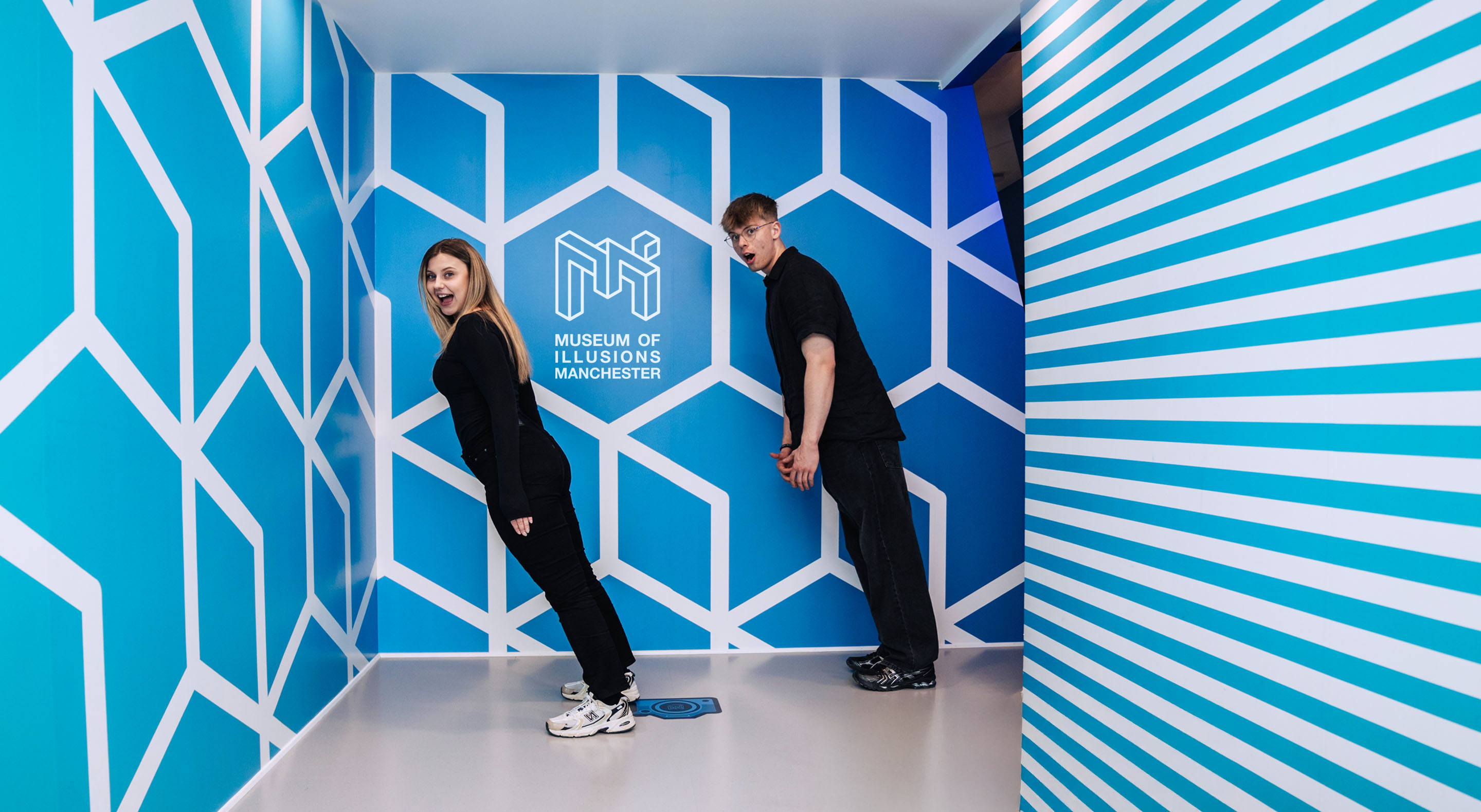 A young couple appears to defy gravity at Museum of Illusions' Tilted Room.