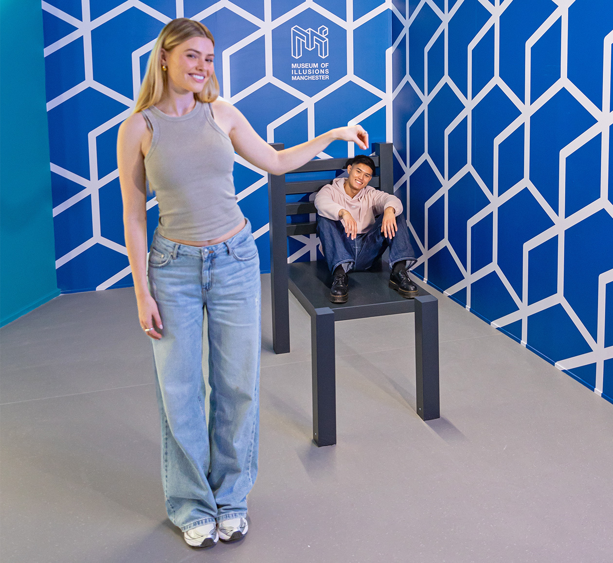A person sitting in the Beuchet Chair looks disproportionately small compared to the person who stands next to it.