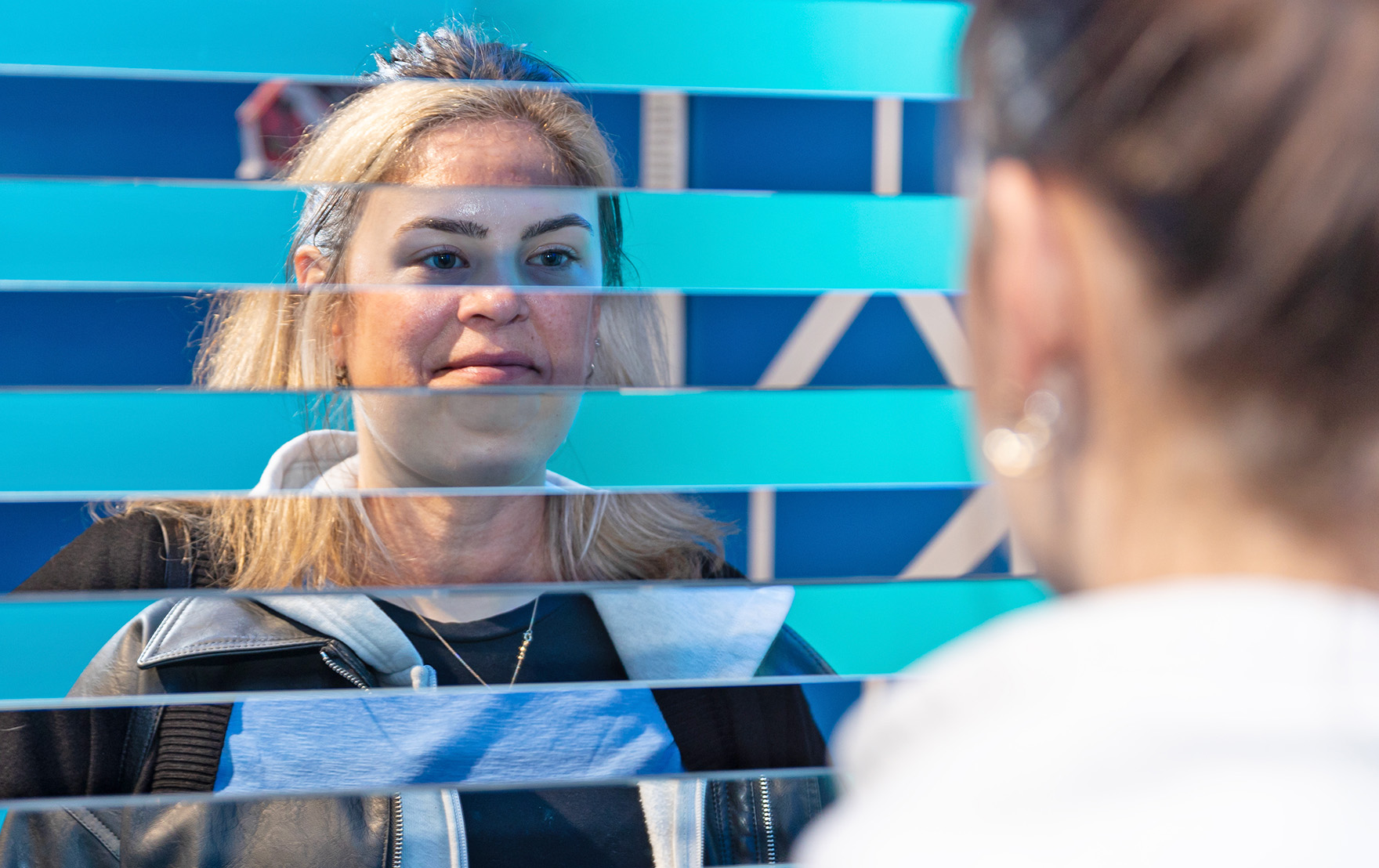 Two people are interacting with the Swap Noses illusion. The exhibit creates a composite image of their faces.